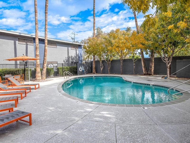 a swimming pool with benches and trees next to a building
