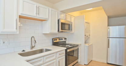 A kitchen with white cabinets and appliances.
