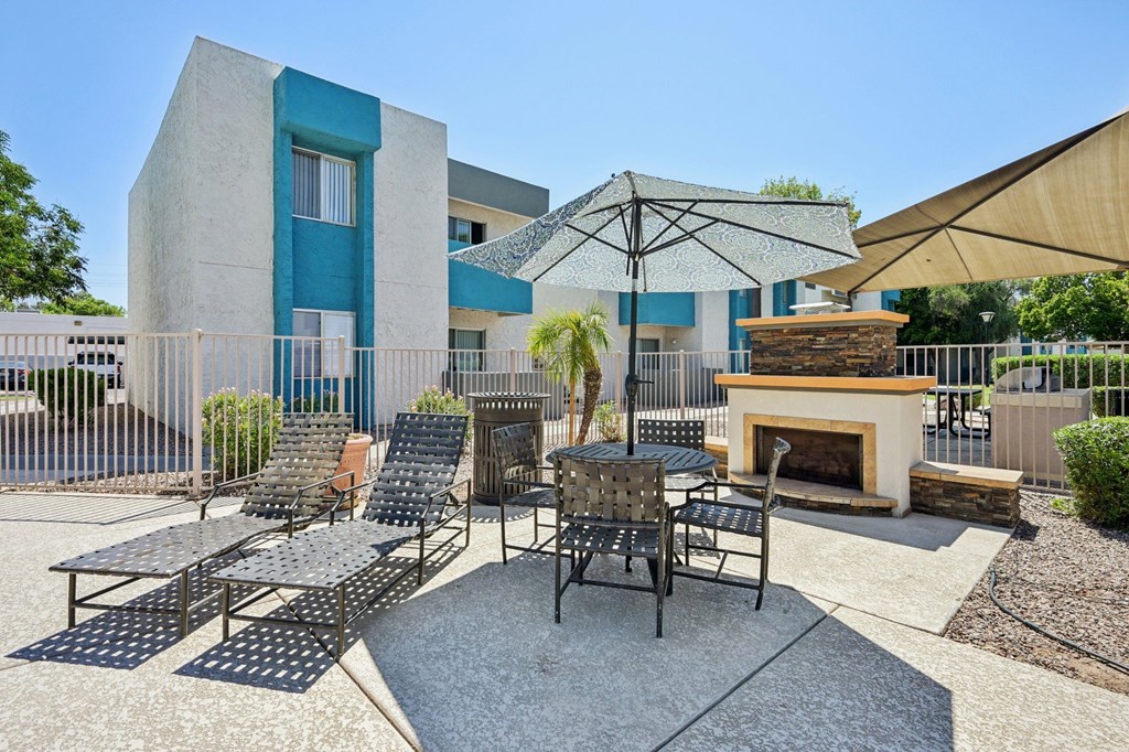A patio with a fireplace and chairs.