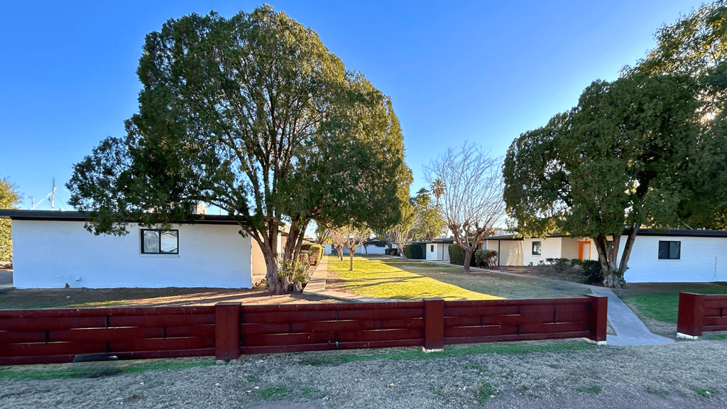 a red fence surrounds a yard in front of a house
