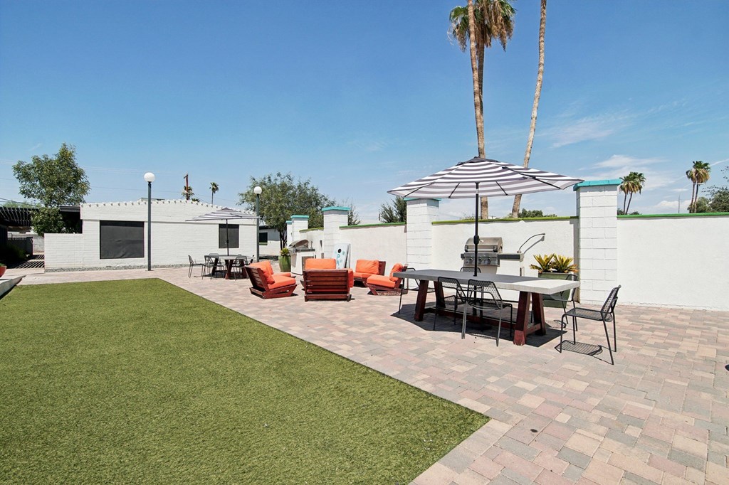 A patio with a table and chairs under an umbrella.