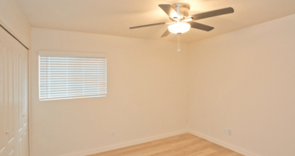 A room with a ceiling fan and a window with blinds.