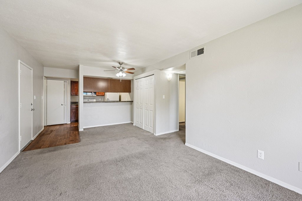A spacious room with a ceiling fan and carpeted floor.