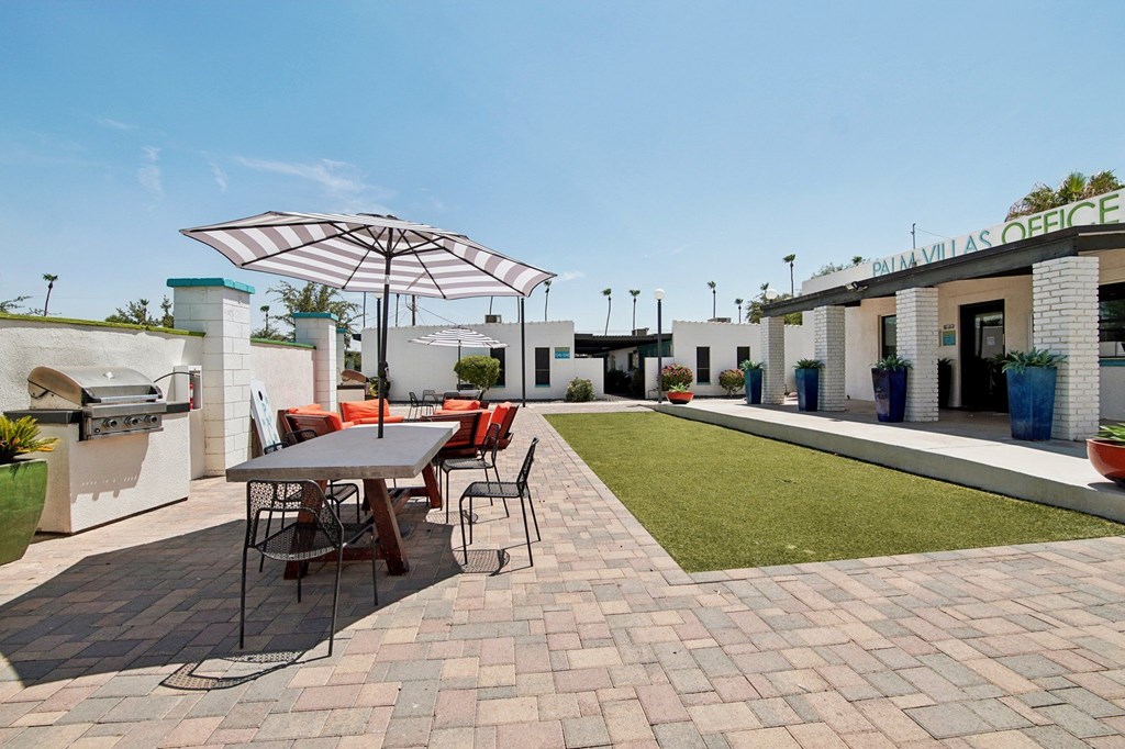 A patio with a table and chairs under an umbrella.