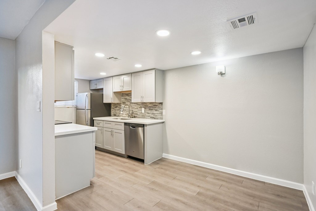 A kitchen with white cabinets and a stainless steel refrigerator.