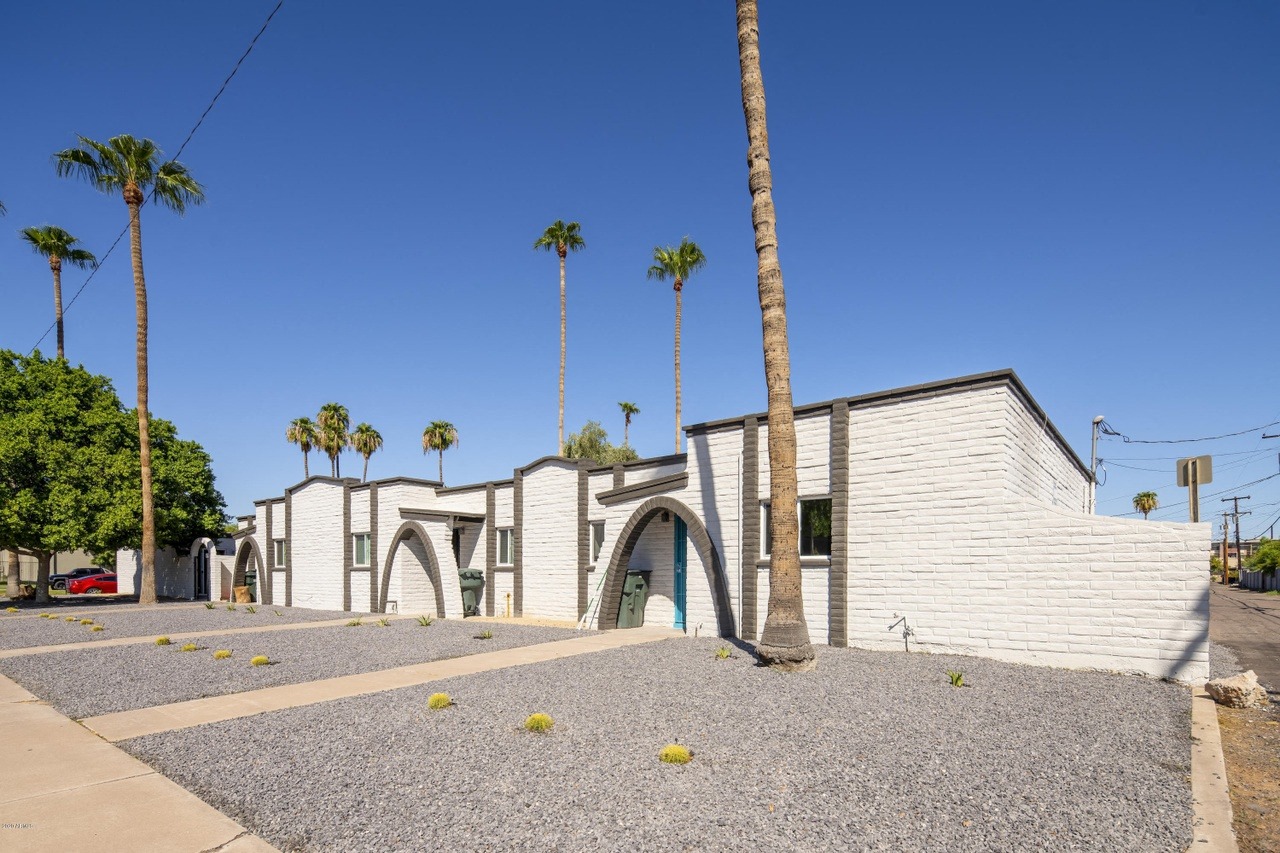 a white brick building with palm trees and a blue sky