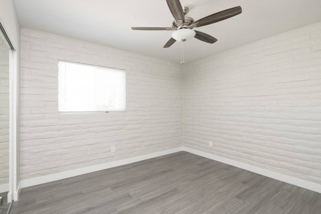 an empty room with a ceiling fan and a window