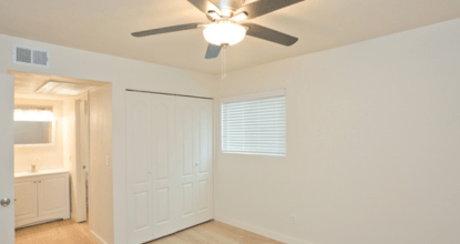 A room with a ceiling fan and a window with blinds.
