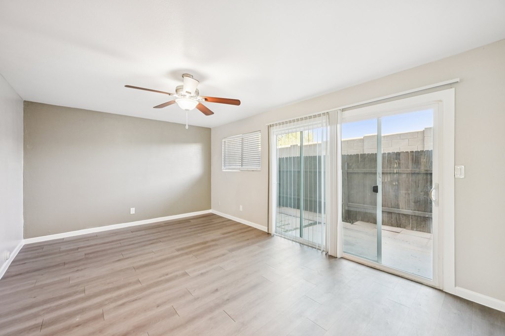 A room with a ceiling fan and sliding glass doors.