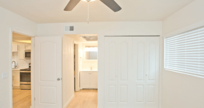 A white room with a ceiling fan and a doorway leading to another room.