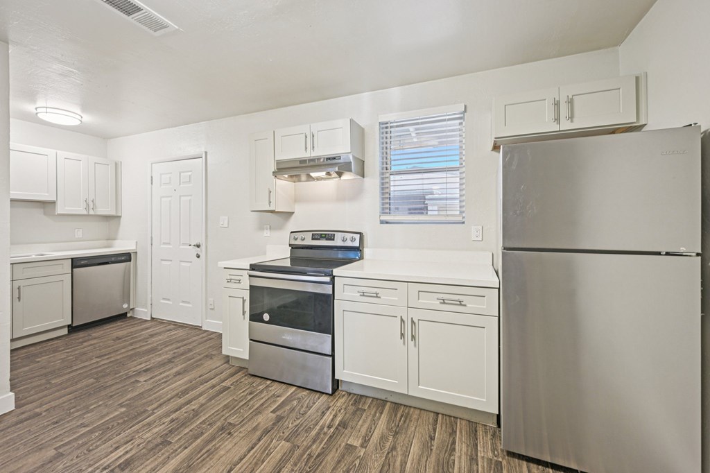 A kitchen with white cabinets and a stainless steel refrigerator.