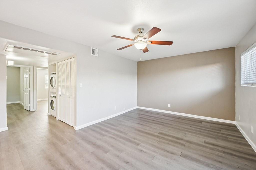 A room with a ceiling fan and light fixture, and a doorway leading to another room.