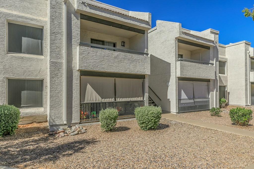 an exterior view of two apartment buildings with a gravel courtyard at Tides on Southern, Mesa Arizona