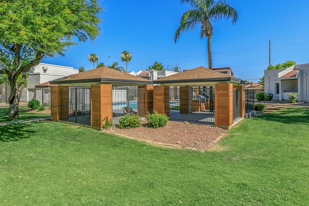 a small house with a gated yard and a palm tree at Tides on Southern, Mesa