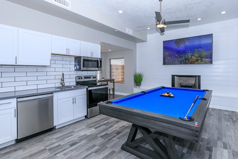 a games room with a pool table and a kitchen