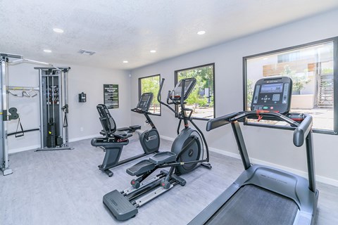 the fitness center with a treadmill, elliptical, and plank flooring with large windows that overlook the patio at Tides on McDowell, Arizona