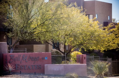 A sign for Bell Minges Estates is in front of a building and trees.