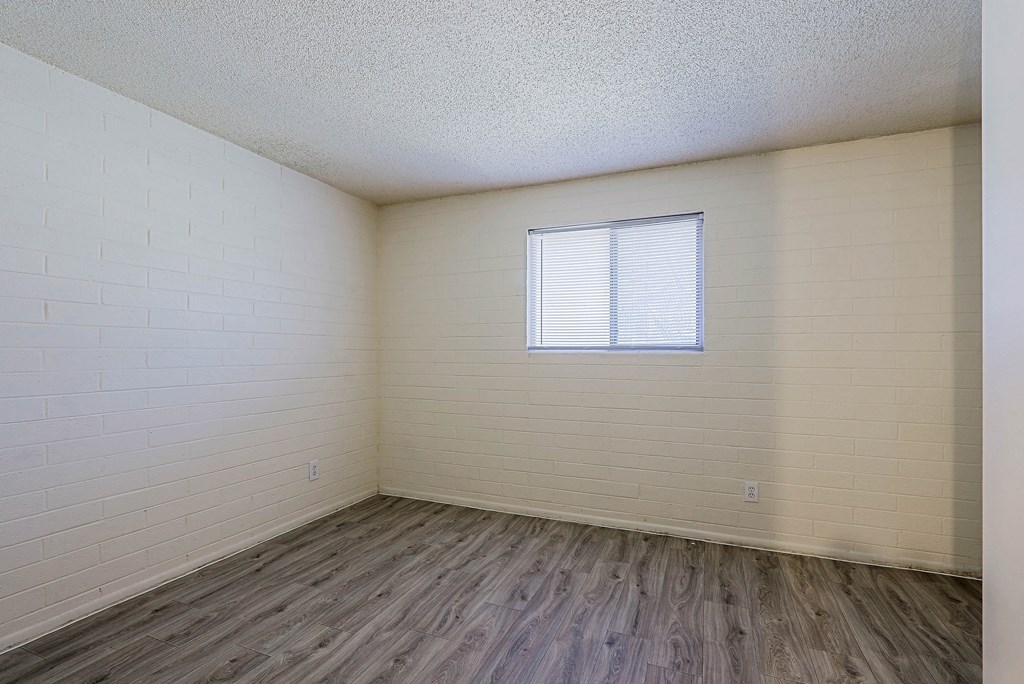 A room with a window and wooden flooring.