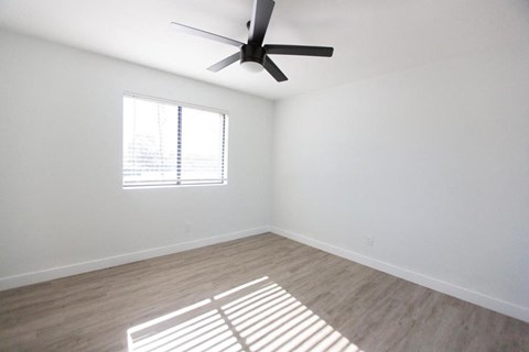 an empty room with a ceiling fan and a window