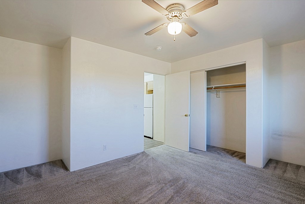 A room with a ceiling fan and carpeted floor.