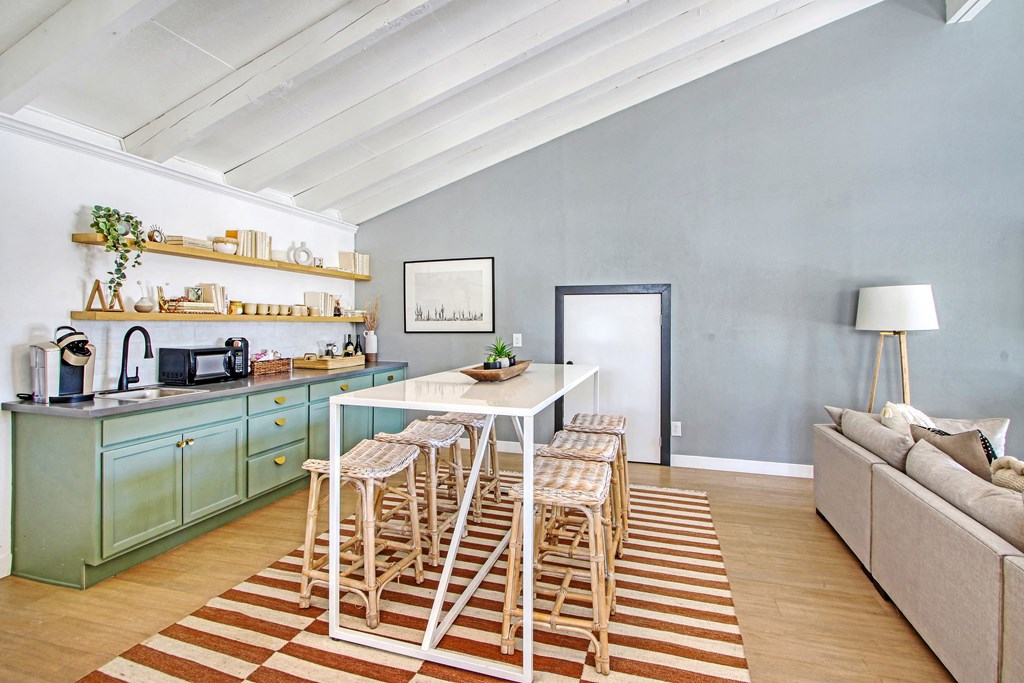 a dining area with a white table and chairs and a kitchen with blue cabinets