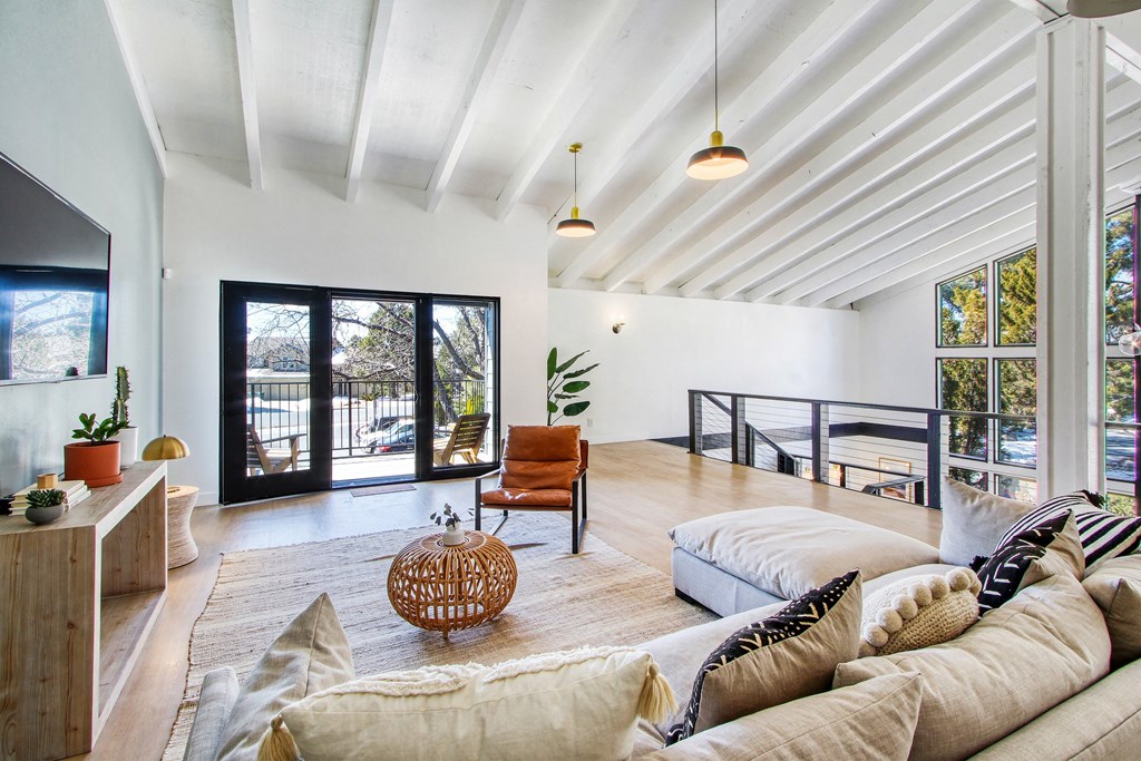 a living room with a couch and a tv and a balcony