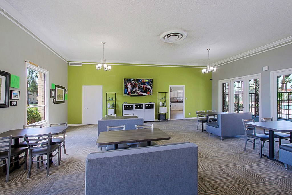 a common room with tables and chairs and a television on the wall