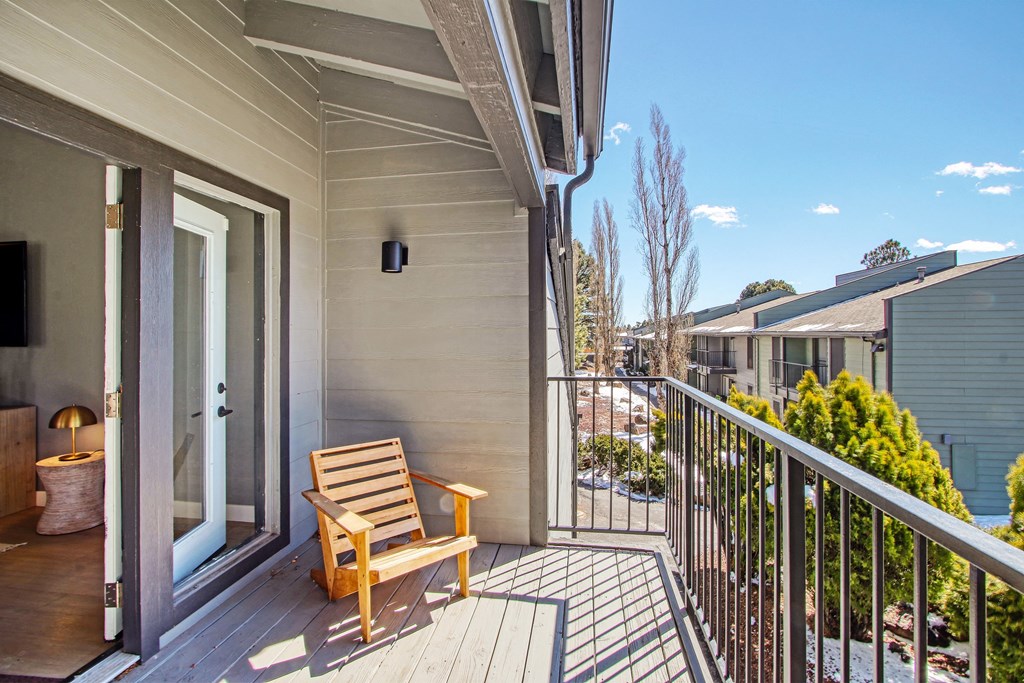 a wooden bench on a balcony with a glass door