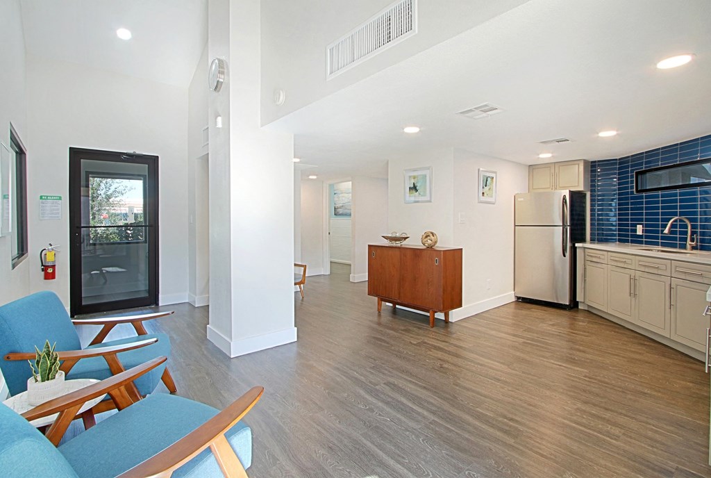 a kitchen and living room with a refrigerator and a table and chairs