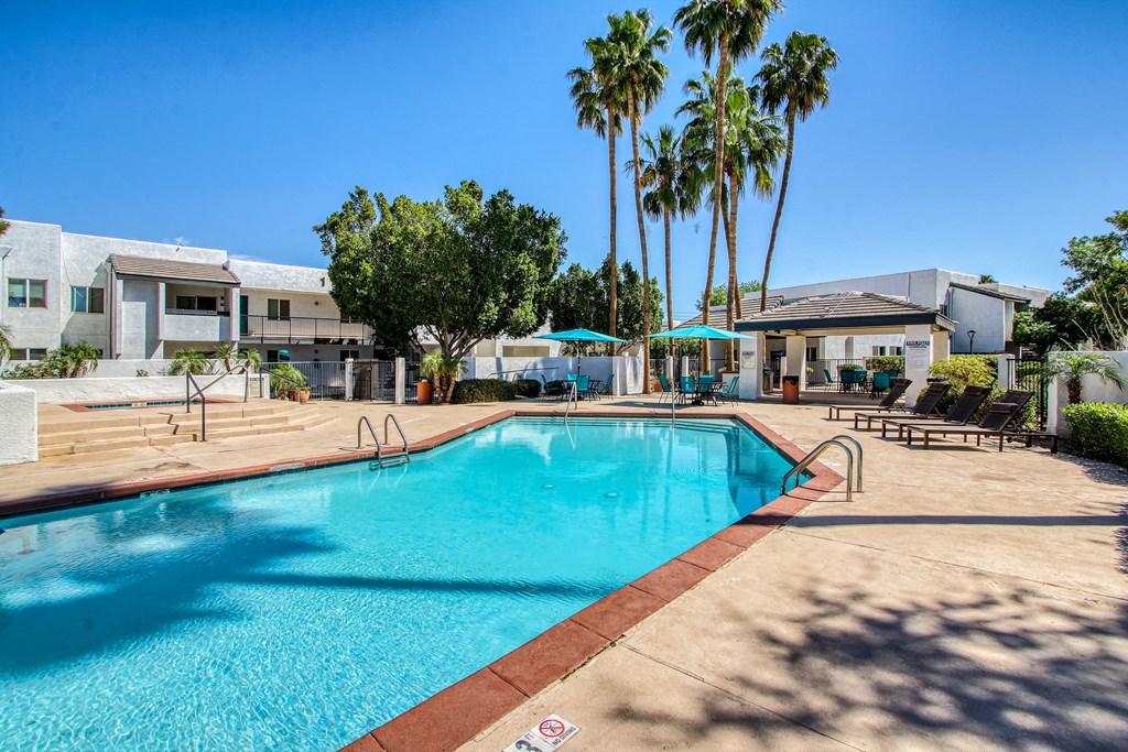 a swimming pool with palm trees and apartments in the background