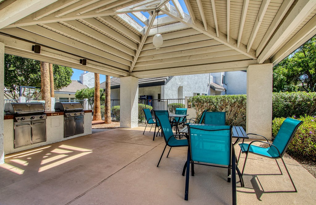 a patio with a table and chairs and a grill