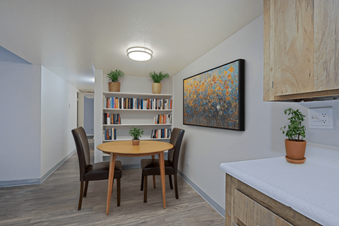 A dining room with a round table and chairs, a bookshelf, and a painting on the wall at Connect on Northern, Glendale, AZ 85301