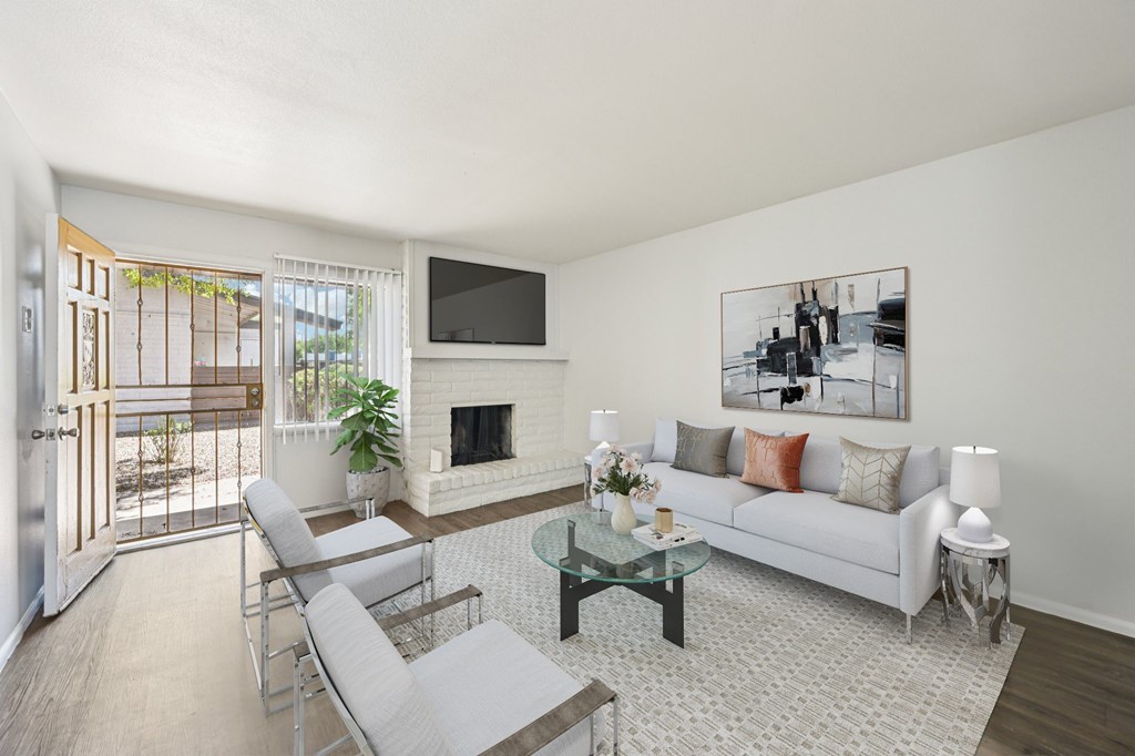 A living room with a white couch, a glass coffee table, and a television.