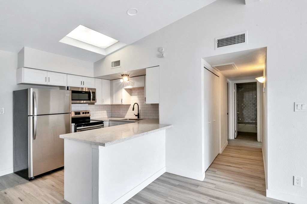 a white kitchen with stainless steel appliances and a large island