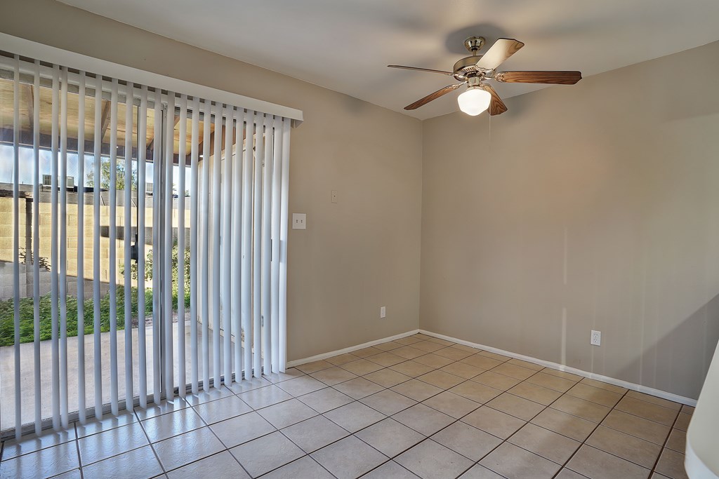 A room with a ceiling fan and a sliding glass door.