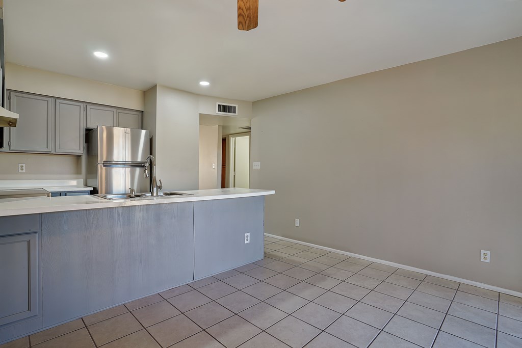 A kitchen with a stainless steel refrigerator and a tile floor.