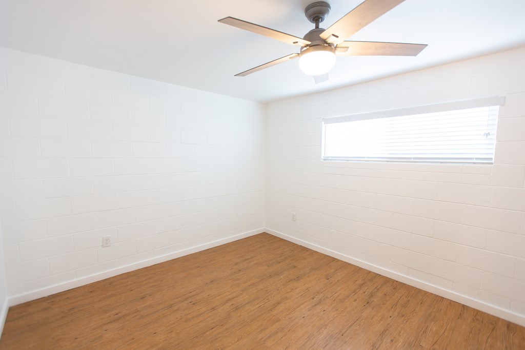 an empty room with a ceiling fan and a window