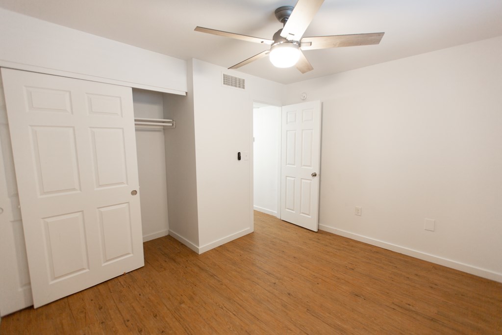 an empty living room with wood flooring and a ceiling fan