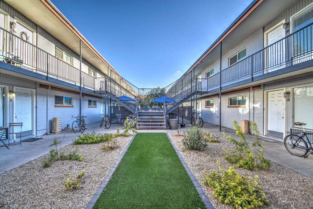 a courtyard between two buildings with a lawn and a staircase