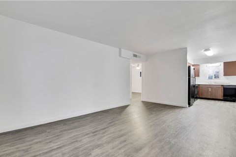 an empty living room with white walls and a refrigerator