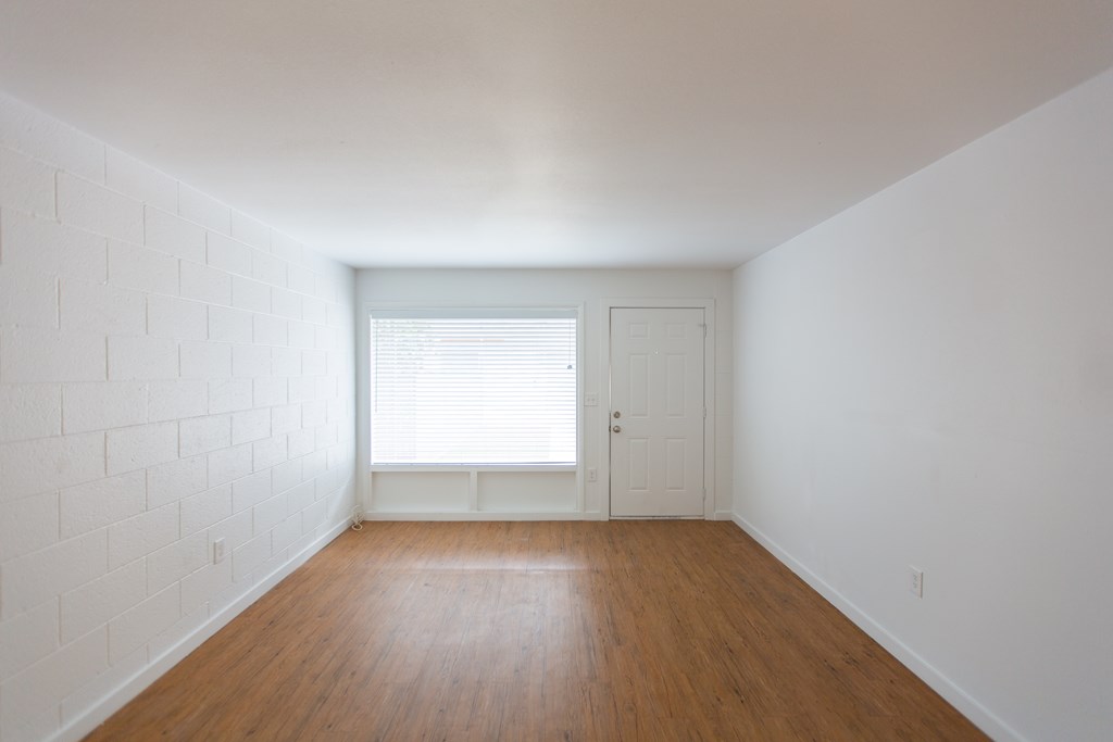 an empty room with white walls and wooden floors and a window