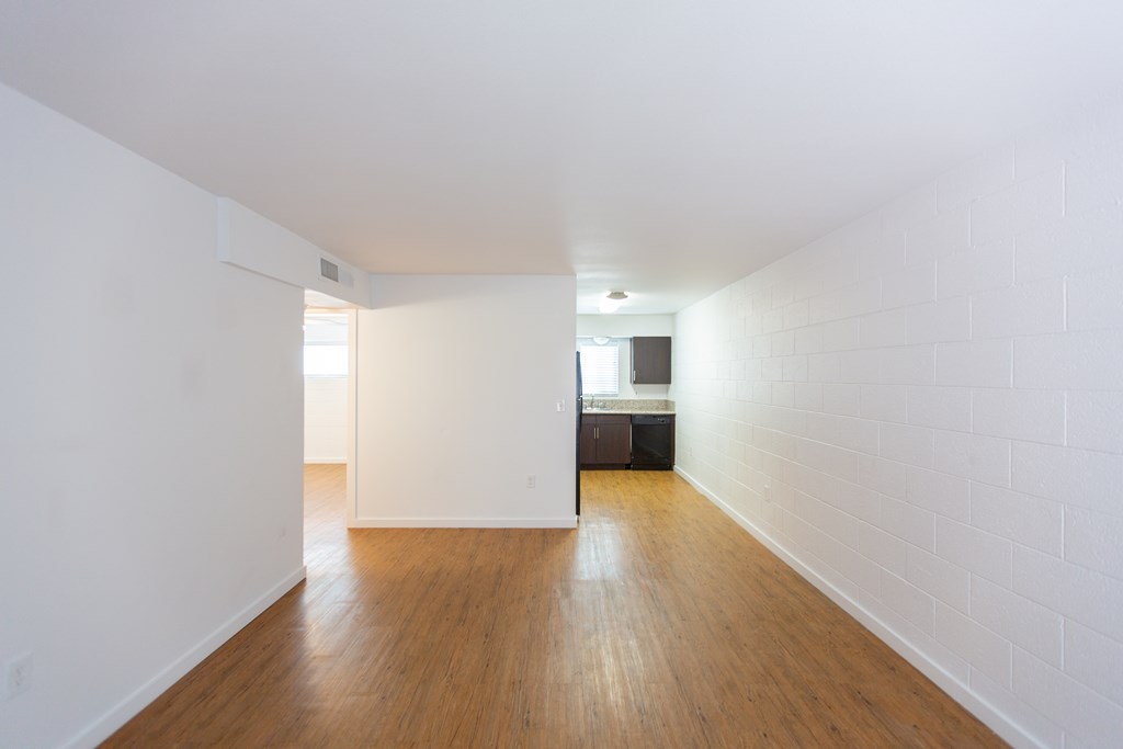 an empty living room with wood floors and white walls