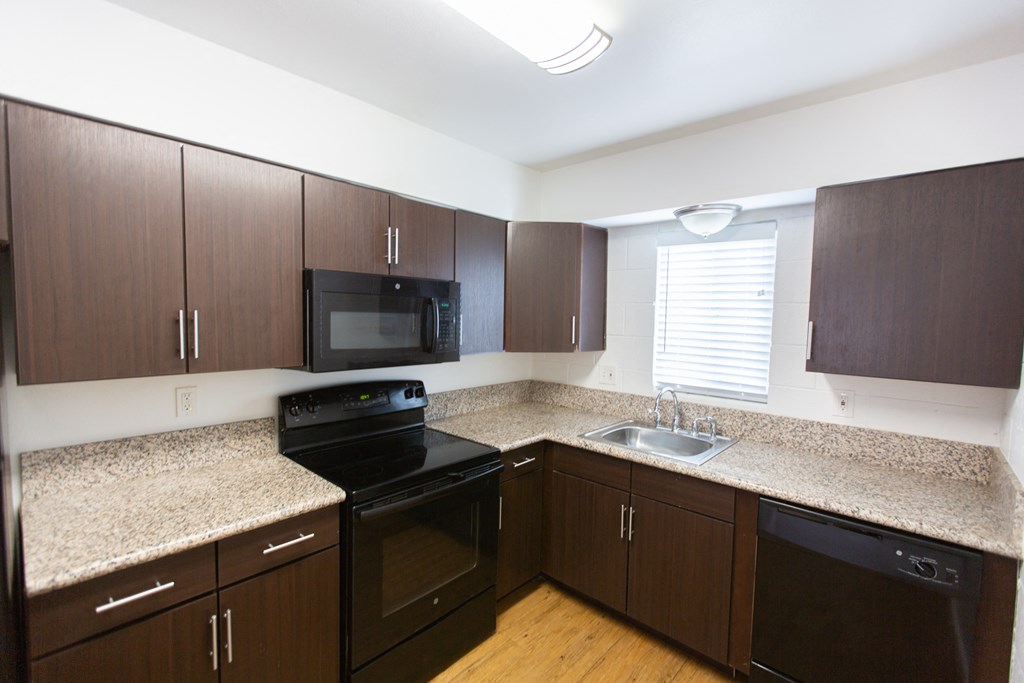 an empty kitchen with granite counter tops and black appliances