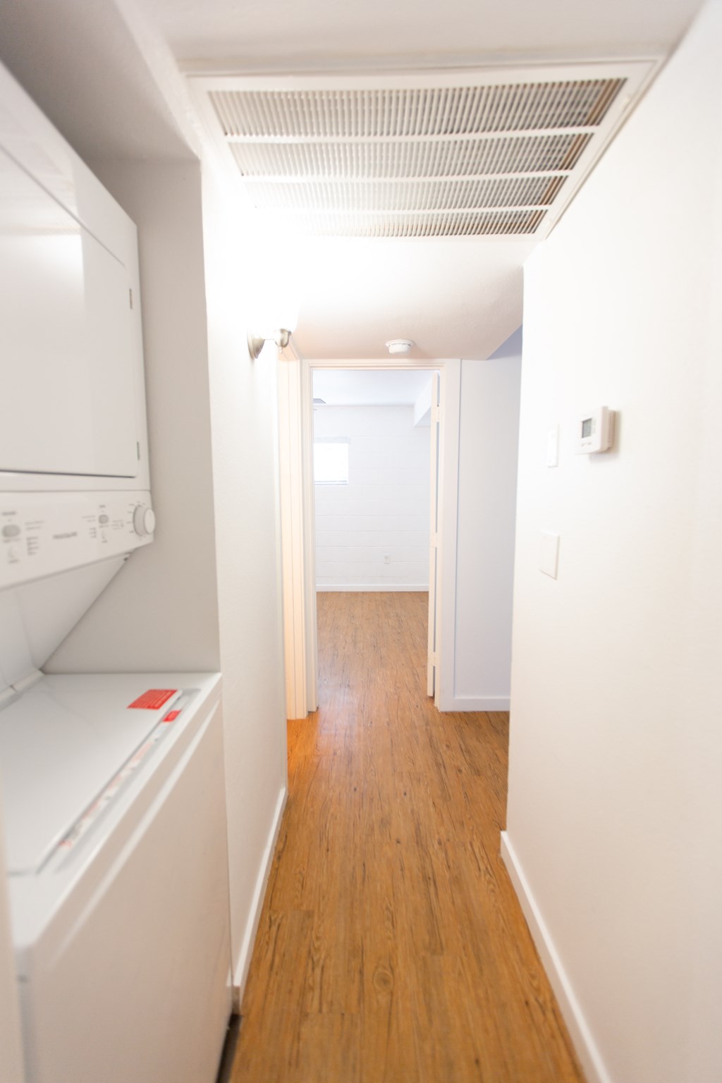 a renovated kitchen with white cabinets and white appliances and a wood floor