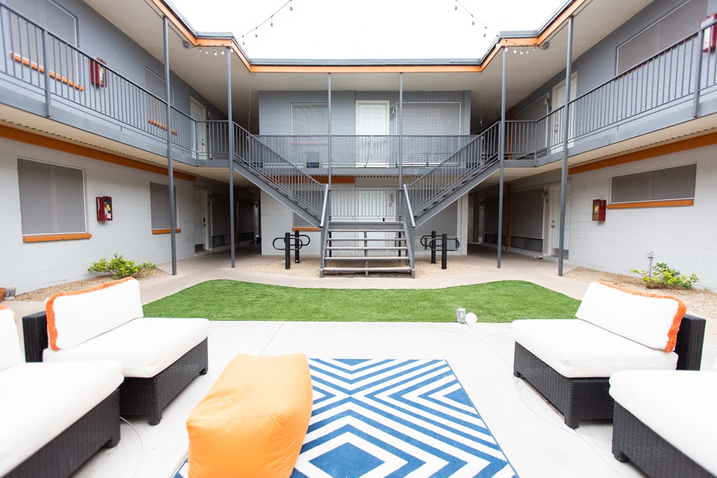 a courtyard with couches and a rug in front of a building