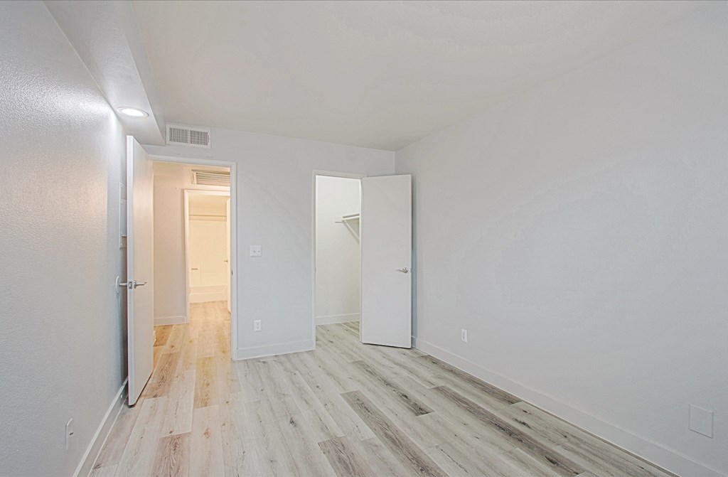 a bedroom with hardwood floors and white walls