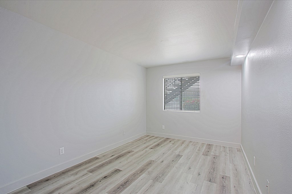 a bedroom with hardwood floors and white walls