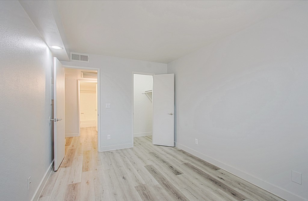 a bedroom with hardwood floors and white walls