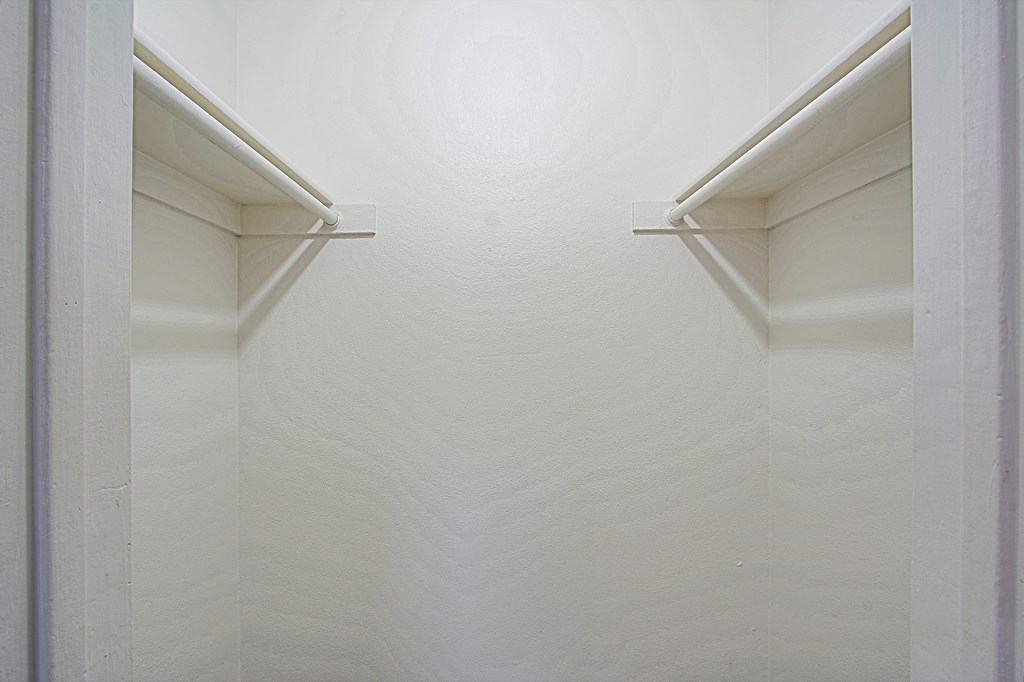 a closet with white walls and two white shelves