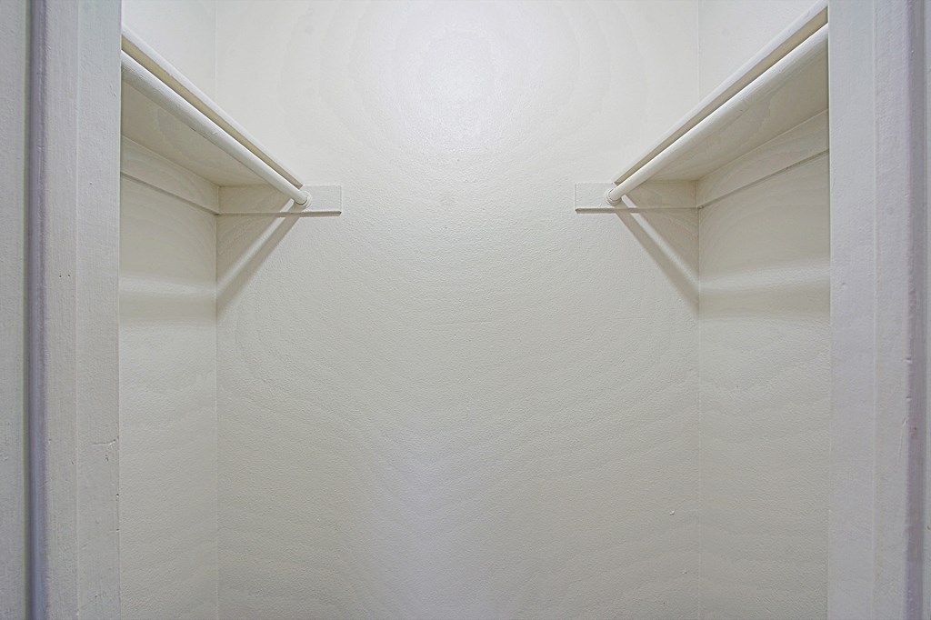 a closet with white walls and two white shelves